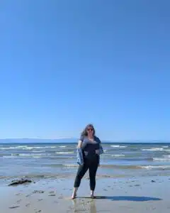 Carly Fielding, For-Sight Marketing Assistant, standing on a sandy beach on a sunny day.
